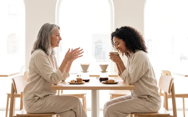 Two people at a table, one speaking and one listening closely over coffee